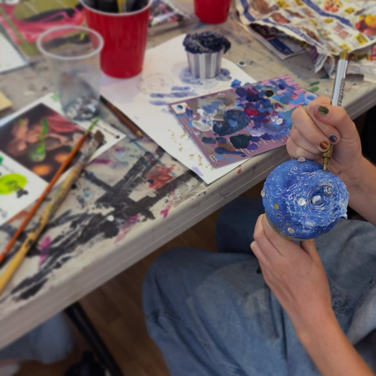 A teen artist painting a hand-built sculpture in the ArtHatch teen studio